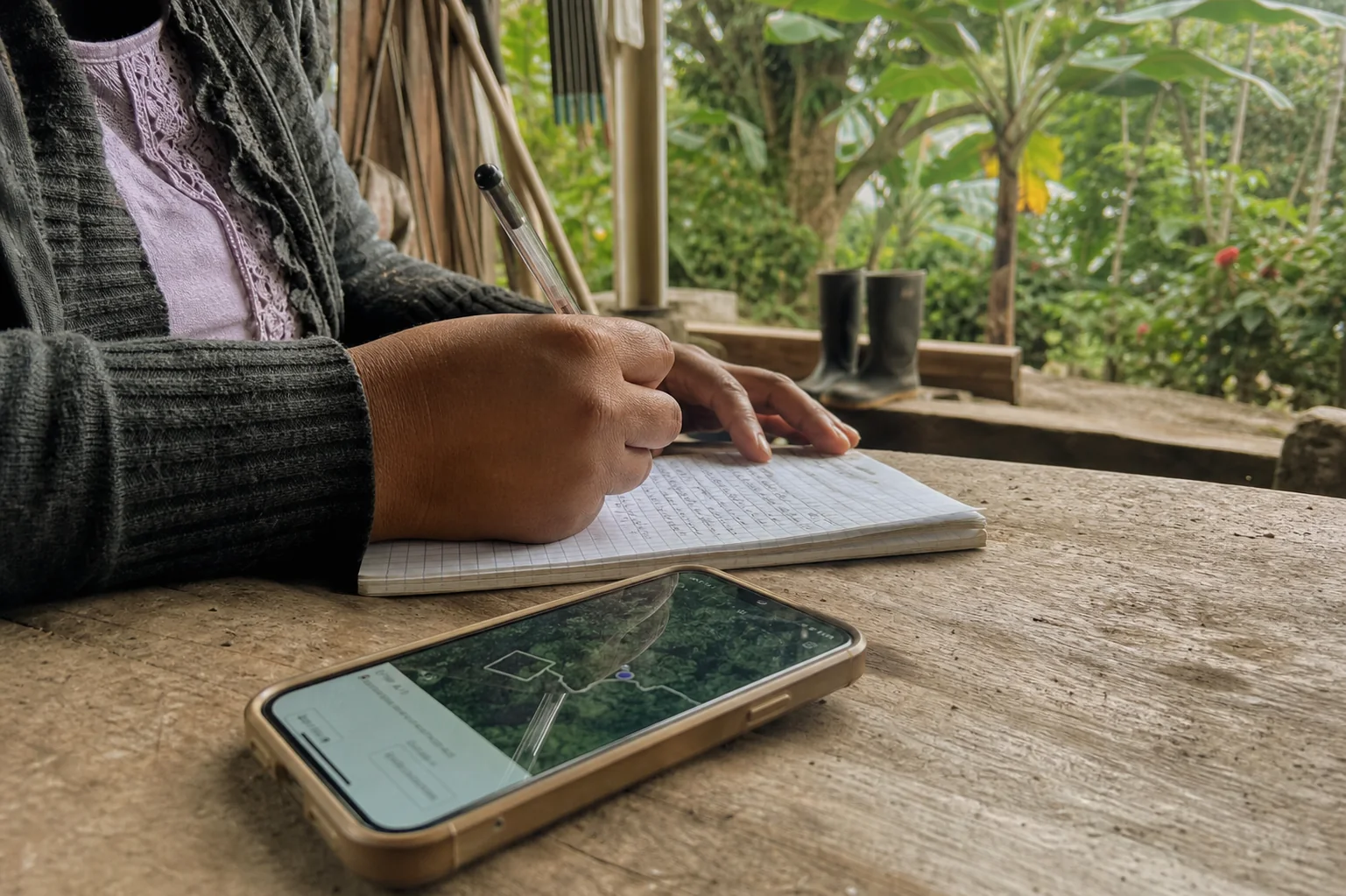 Manos registran información de campo junto a un mapa digital en una finca antioqueña